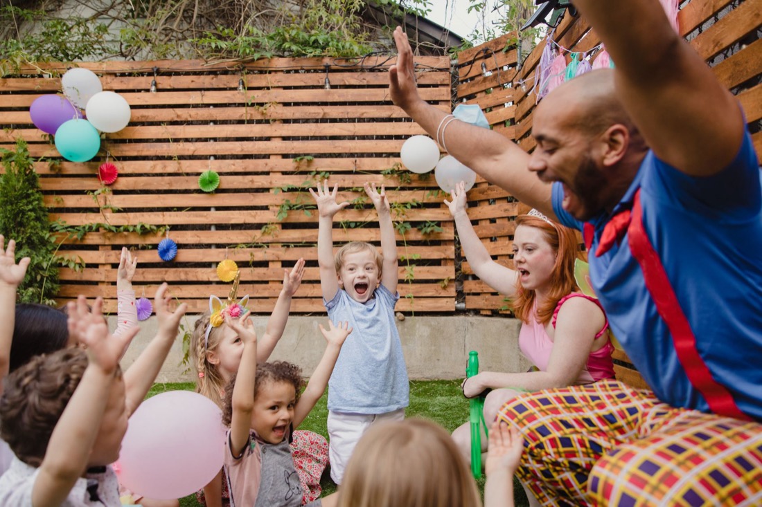 Kids cheering at a backyard birthday party with balloons