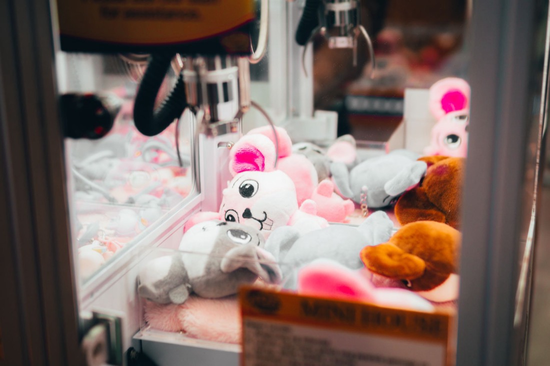 A claw hanging over plush toys inside a claw machine